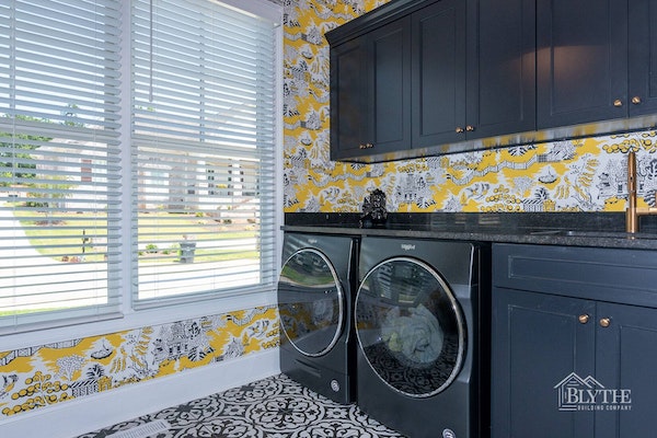 Luxury laundry room with black custom build-in cabinets, black counter, and black sink