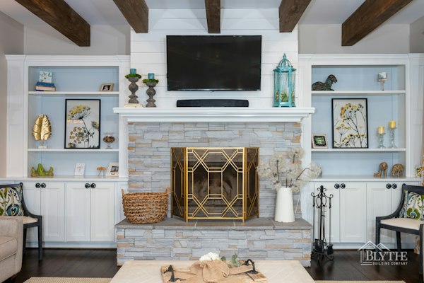 Stacked stone veneer fireplace surround with white crown molding mantel and built-in bookcases on each side of the fireplace with a shiplap fireplace wall