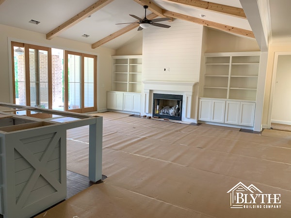Great room under construction with ceiling beams and built-in cabinets