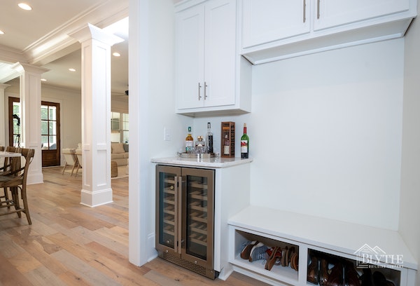 Mudroom with white built-in bench seat and wine cooler near kitchen