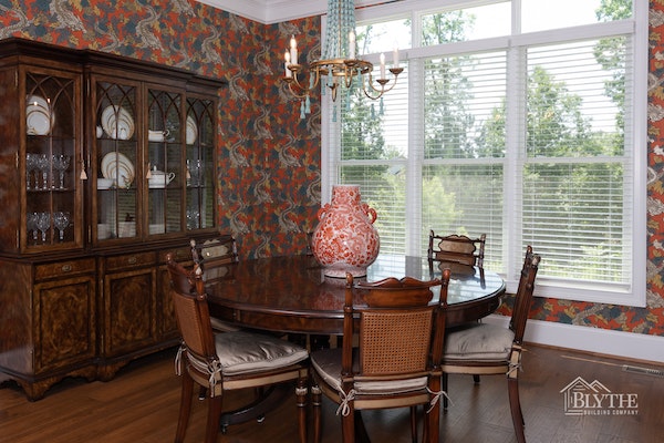 Dining room with bold red dragon motif wallpaper and hardwood floors
