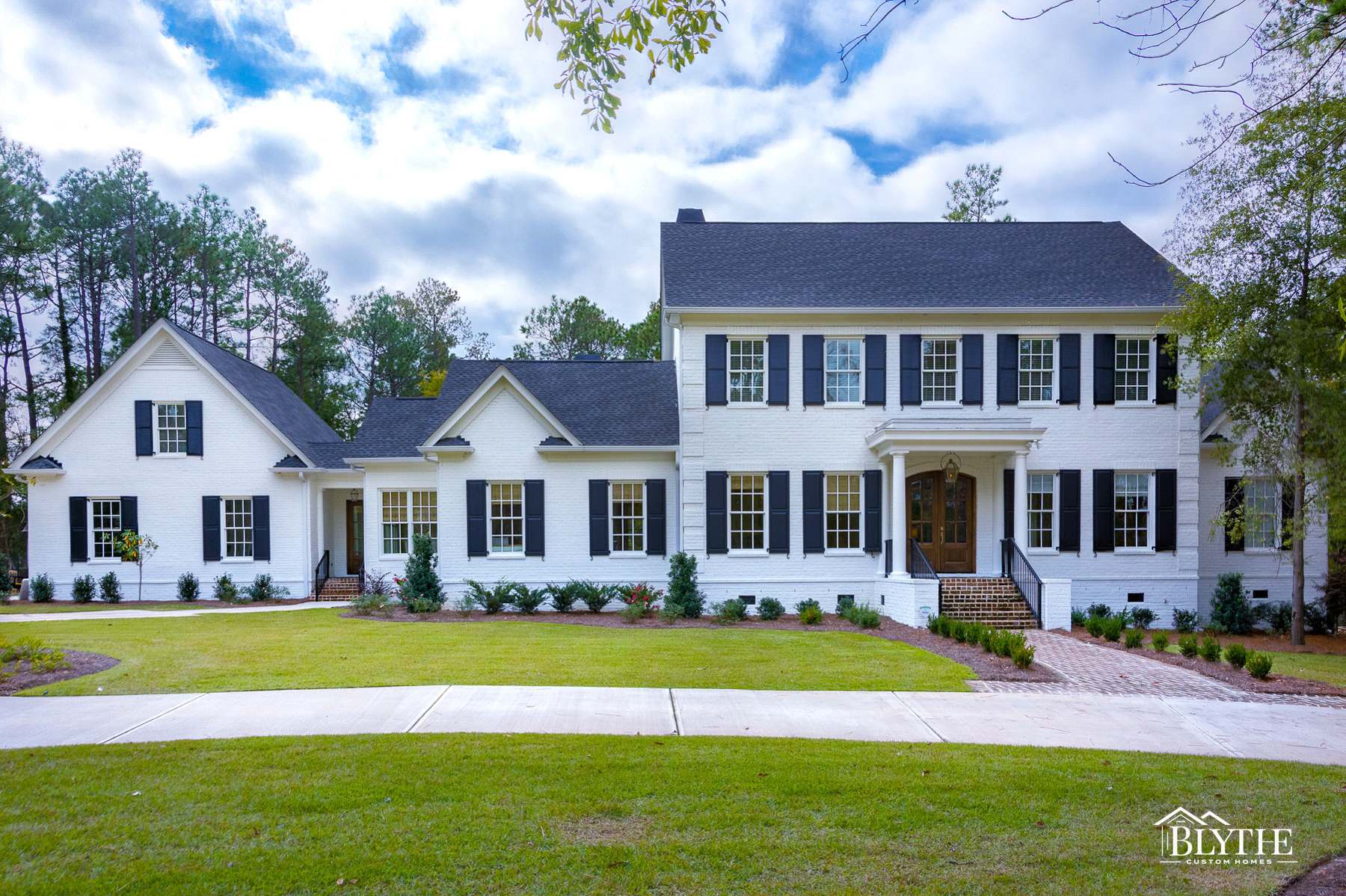 2-story white-painted brick colonial with black shutters and semi-circular driveway.