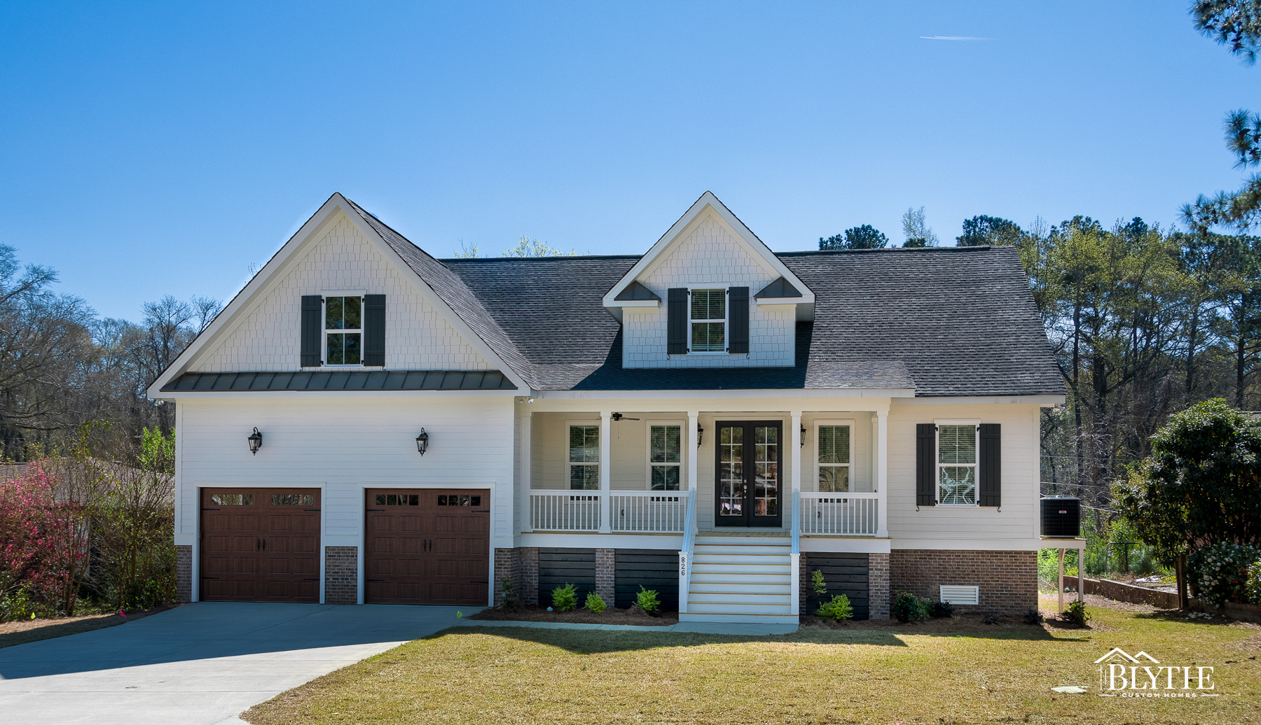 White 2-story Modern Craftsman with mahogany garage doors, a large dormer window, and a front porch with steps.