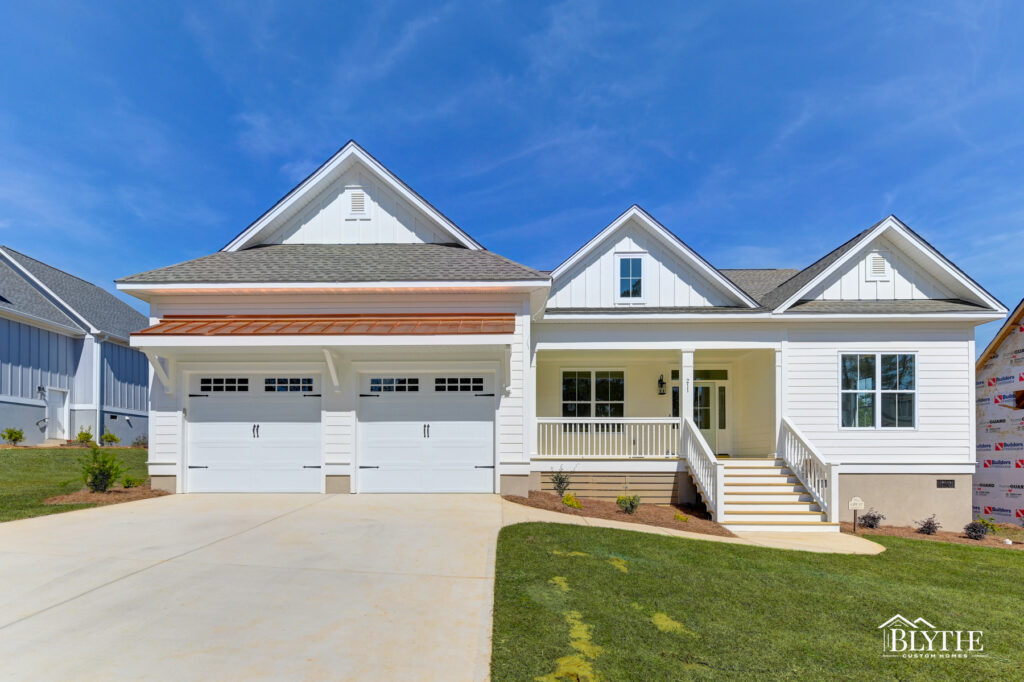 Modern Craftsman home with 3 gables in the front, a copper roof accent over the 2-car garage, and porch with staircase leading to the front yard.