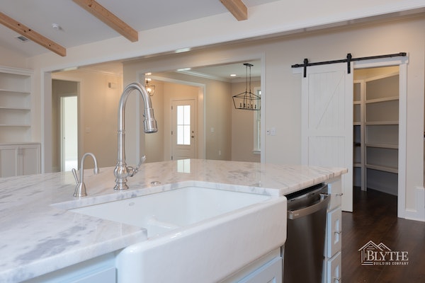 farmhouse-kitchen-sink-and-barn-door-with-panty-and-ceiling-beams.jpg