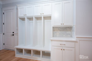 Mudroom with custom bench and 4 cubbies and 4 cabinets overhead and a cabinet and counter beside it with hardwood floors.