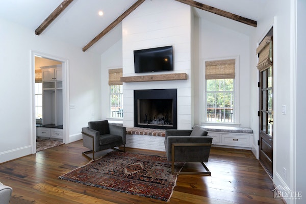 a shiplap fireplace wall, wood mantel, and painted brick hearth with custom window seats beside fireplace