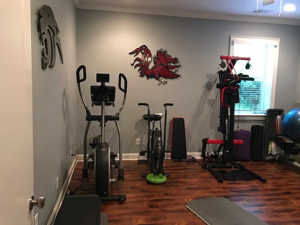 Custom home gym with stationary bike and weight machine and hardwood floors