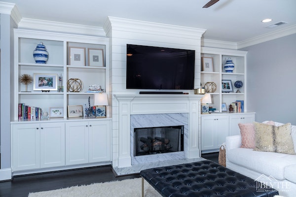 White fireplace surround with columns and a crown molding shelf with an inner marble fireplace surround, and floor-level hearth and shiplap fireplace wall.