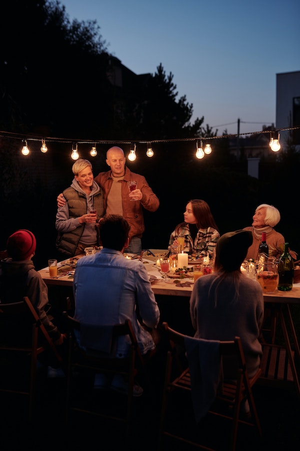 family-Thanksgiving-celebration-outside-with-string-lights-at-night