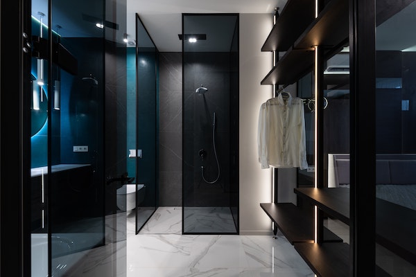 Black, modern, luxury walk-in closet with backlighting and modern bathroom