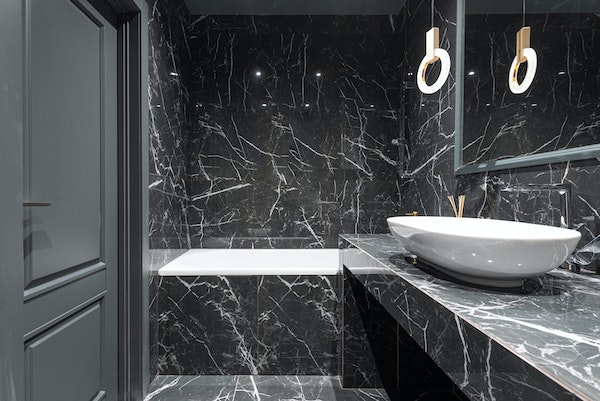 Black marble bathroom with marble walls, marble floor, and marble countertop