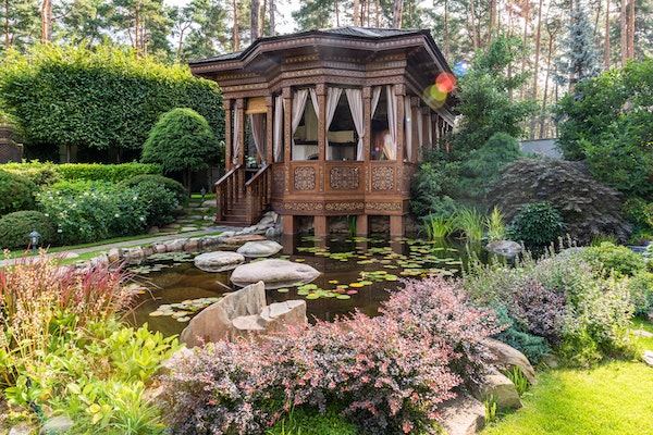 Asian gazebo-style deck with curtains overlooking pond with lilypads
