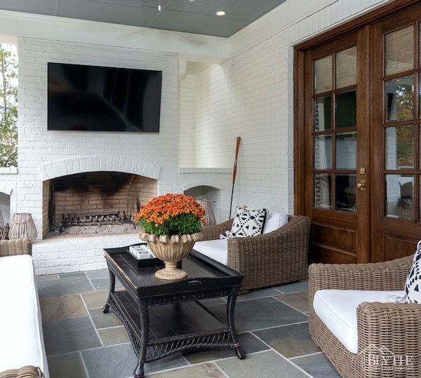 white painted brick back porch with masonry fireplace and outdoor TV with living space