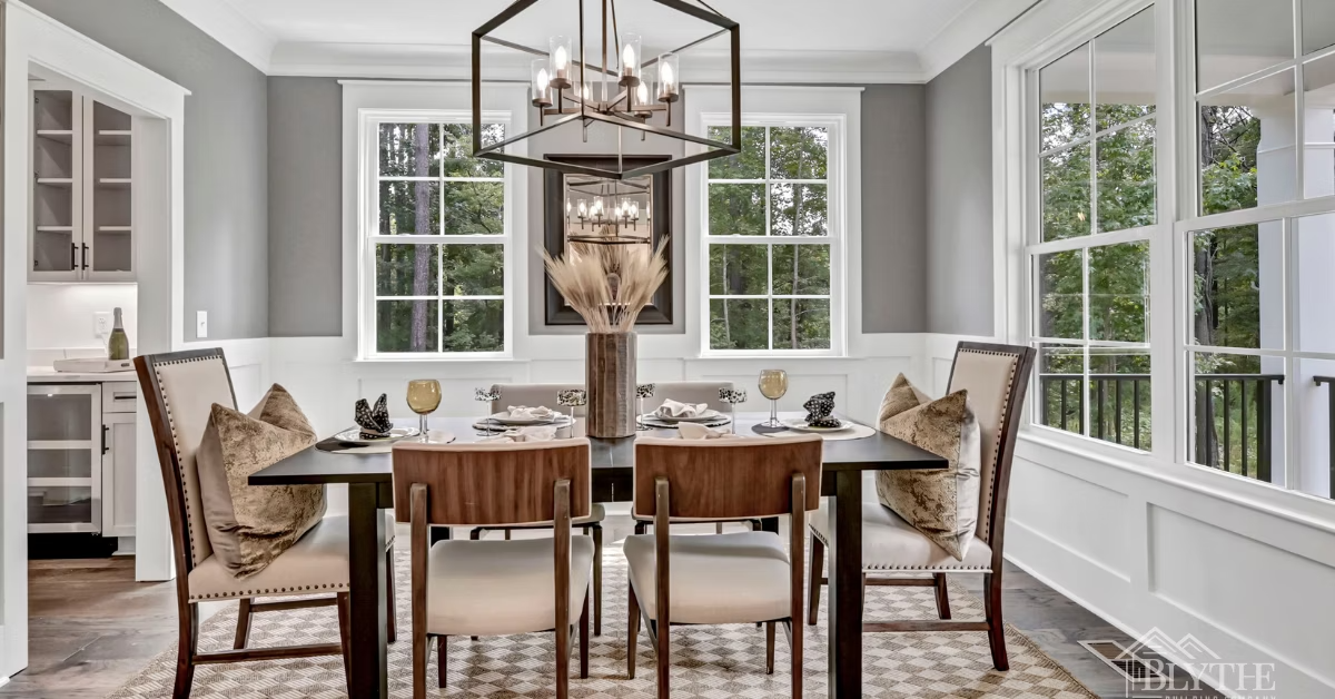 A Modern Craftsman formal dining room wtih heavy wood molding, trim, and wainscoting, and a rustic wood floor, a table for 6, and an oversized black metal chandelier.