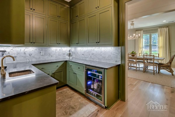 Scullery With Green Cabinets And Wine Cooler And Rustic Hardwood Floors