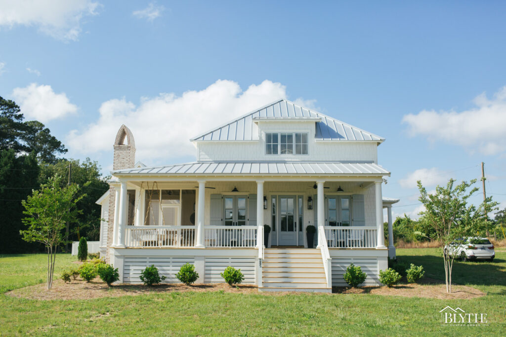 Front exterior Lowcountry-style home with large front porch, metal roof, and a shed dormer on a flat, grassy lot.