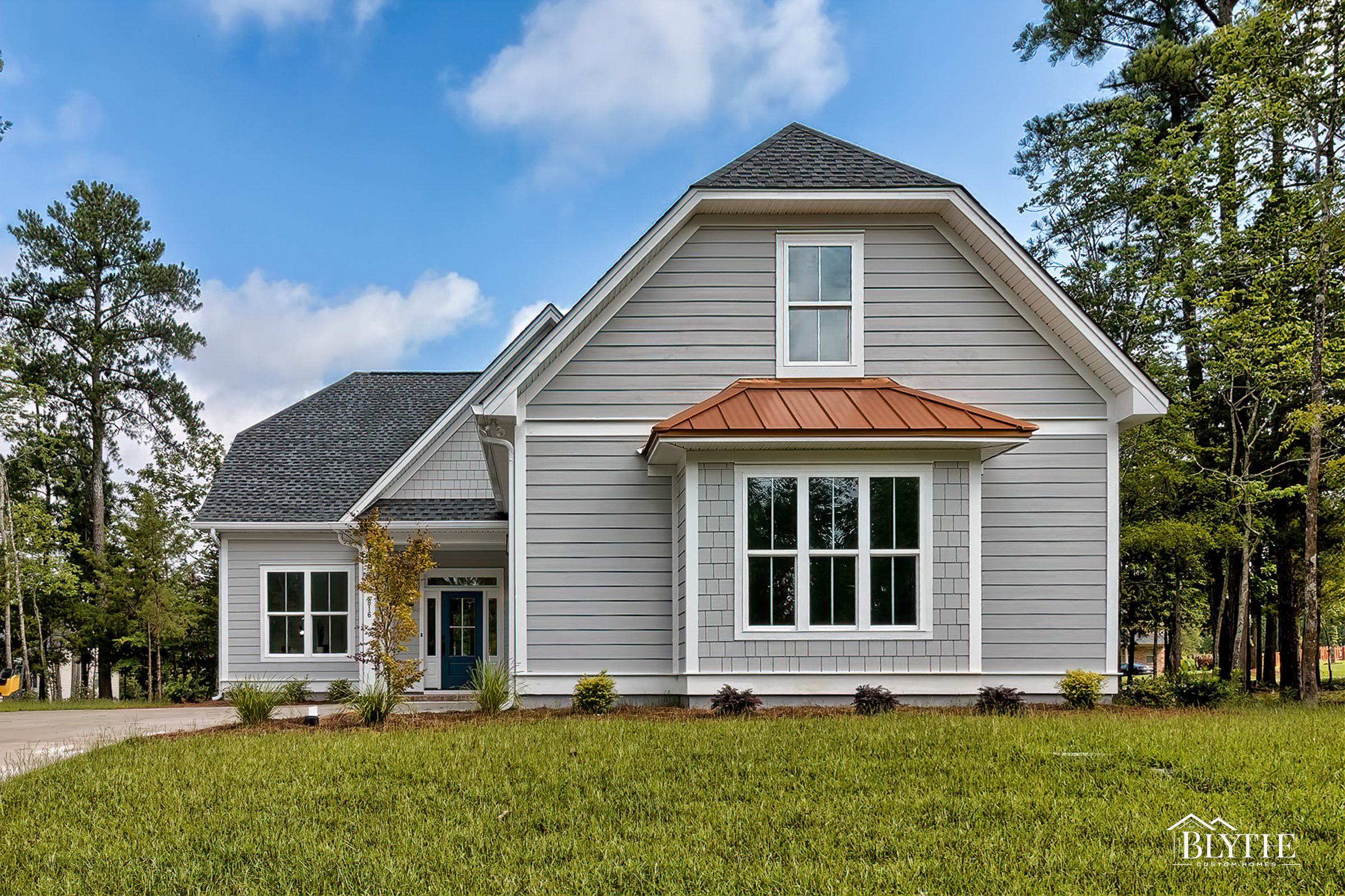 Front exterior of Modern Craftsman home with gray Hardie plank siding and some shake accents and copper roof accent over box window